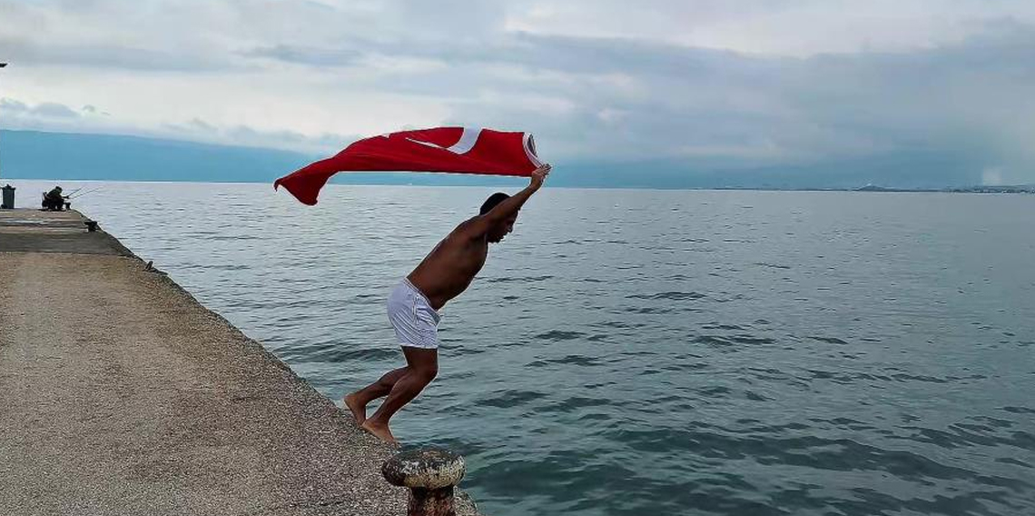 Soğuk ve yağışlı havaya aldırmadı, Türk bayrağıyla denize girdi
